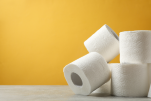 toilet paper rolls stacked in front of a yellow wall